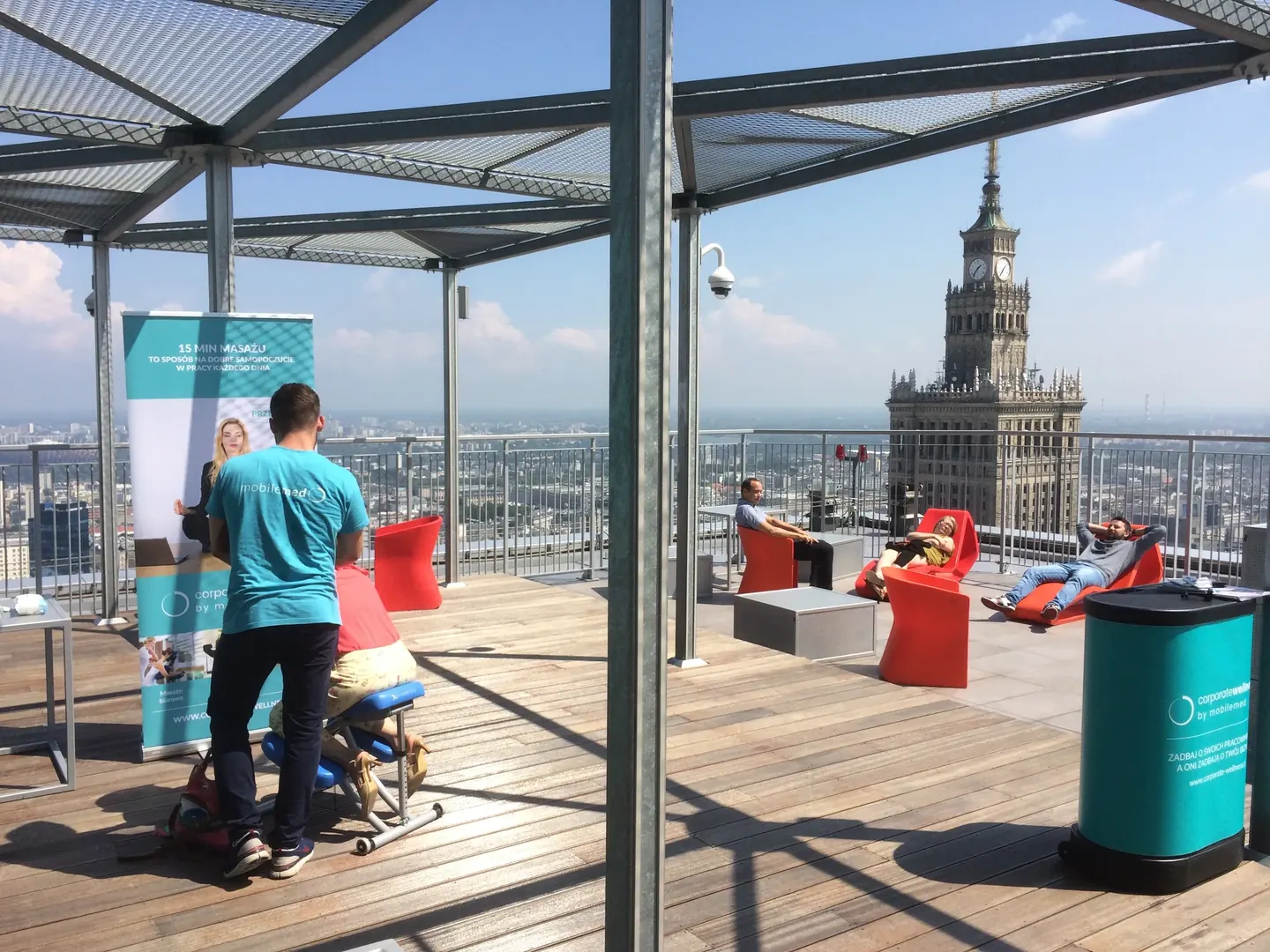 Masaż na krześle na tarasie biurowca, w tle Pałac Kultury i Nauki